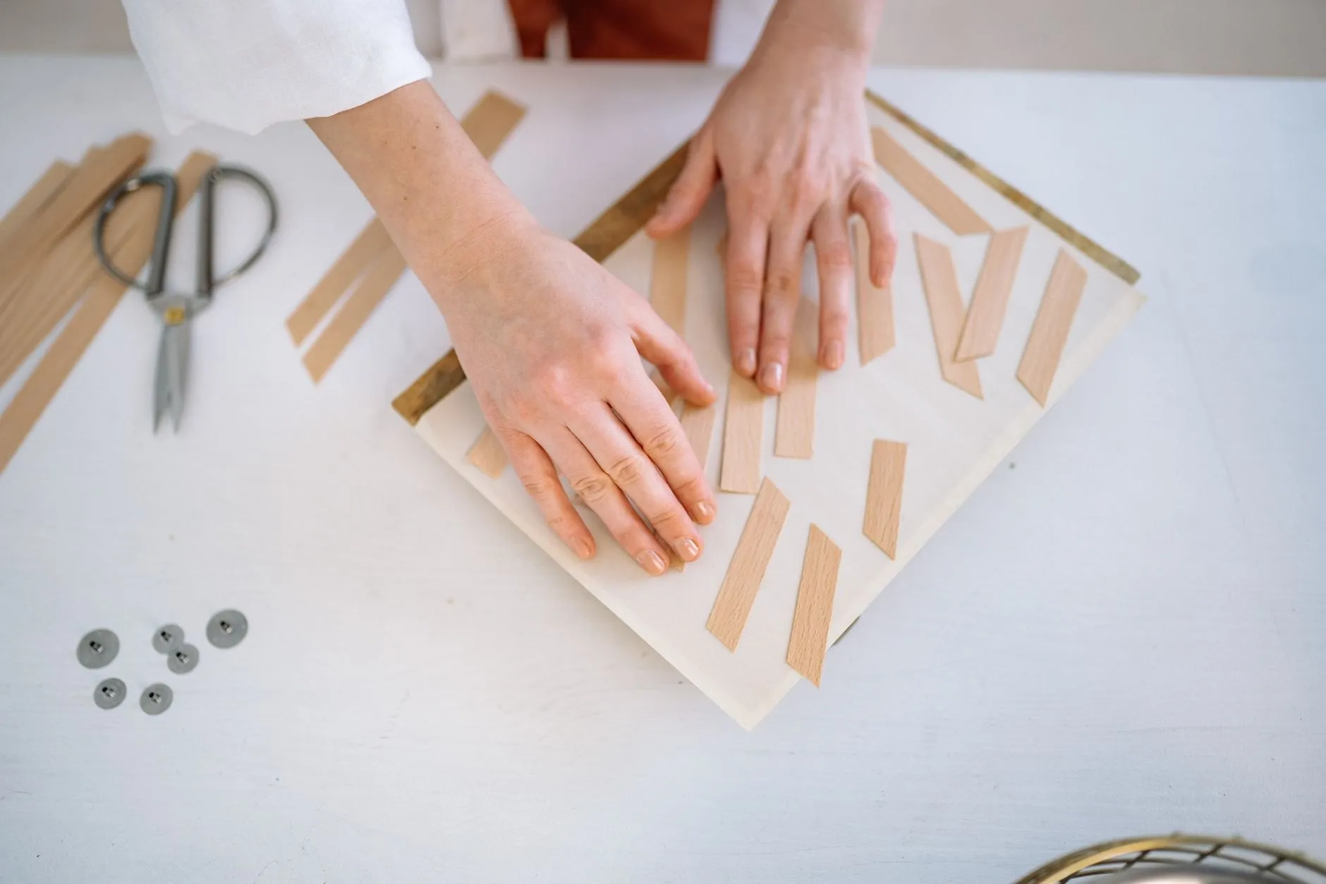Hands laying cut paper blotter strips in a row on a white board