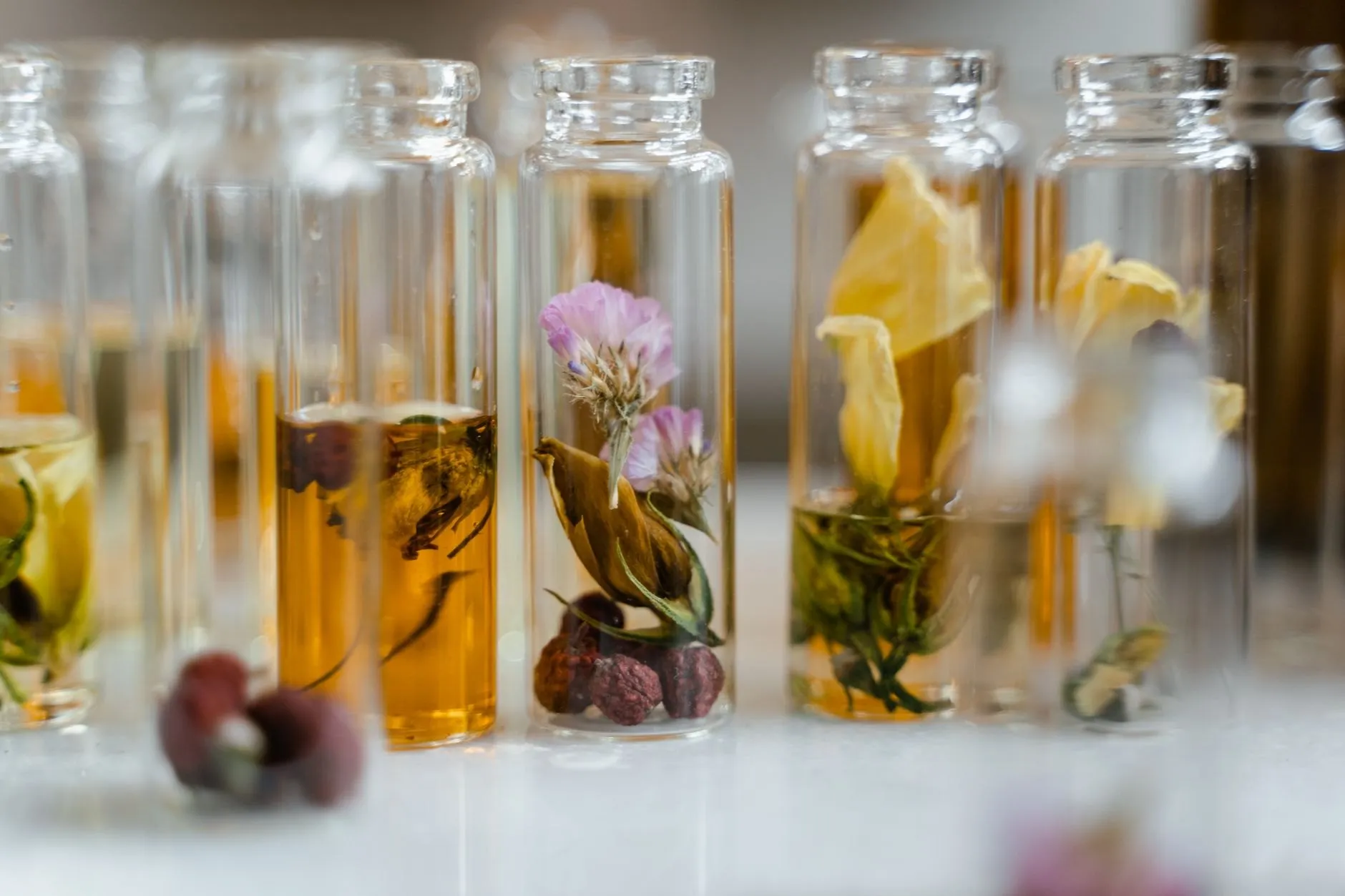 Small glass vials of fragrance infusions lined up on a marble slab